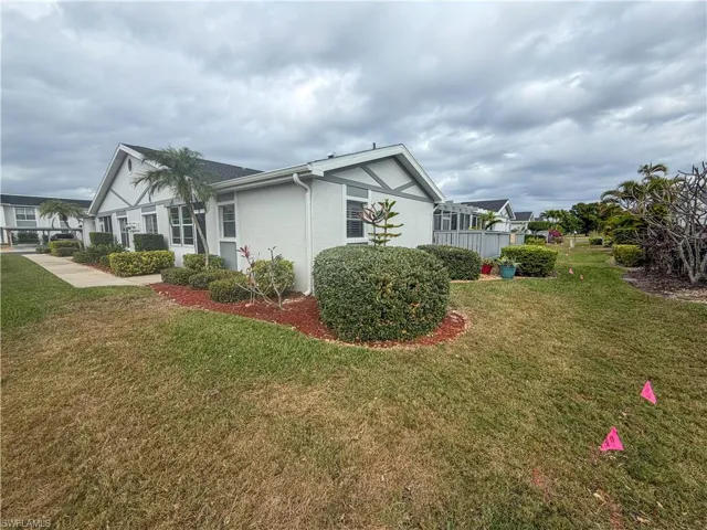 View of side of property with a lawn and stucco siding