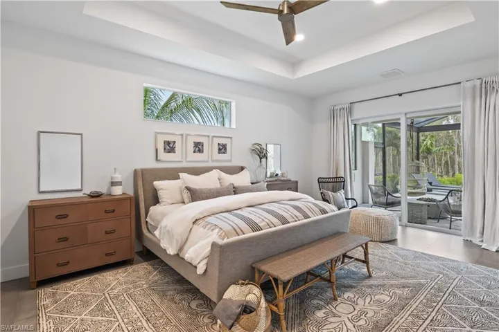 Bedroom featuring tile floors, ceiling fan, access to exterior, and a tray ceiling