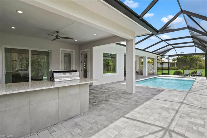 View of pool with ceiling fan, glass enclosure, area for grilling, and a patio