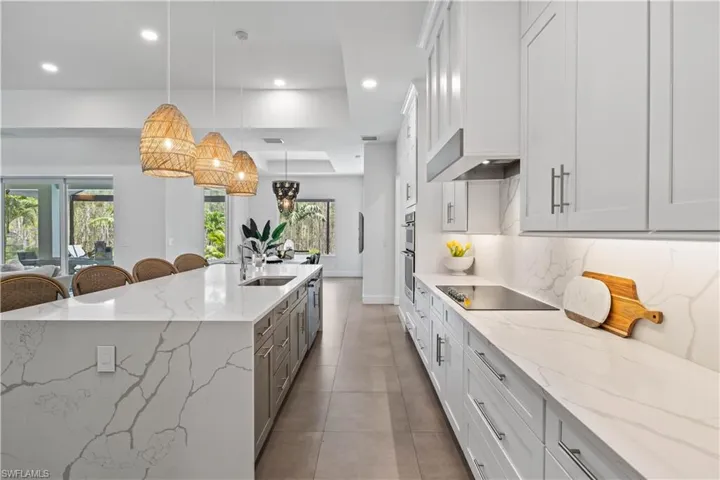 Kitchen featuring appliances with stainless steel finishes, a kitchen island with sink, pendant lighting, tasteful backsplash and tile floors