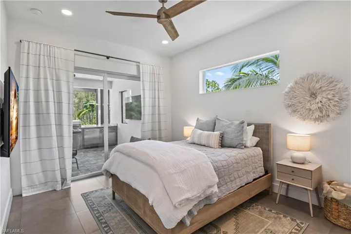 Bedroom with access to outside, tile flooring, ceiling fan and side transom window.
