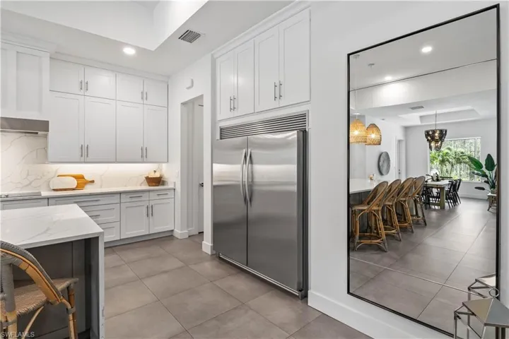 Kitchen featuring white cabinetry, Quartz marble look countertops,stainless steel built in fridge, tasteful backsplash, and a raised ceiling