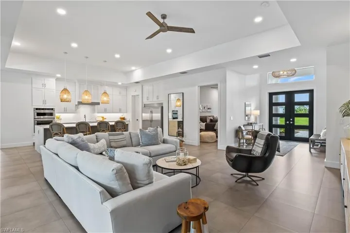 Living room featuring french doors, light tile flooring, ceiling fan, and a raised ceiling