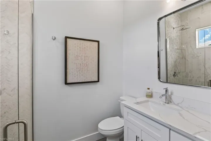 Bathroom with walk in shower, toilet, and large vanity