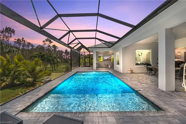 Pool at dusk featuring full length custom Mansard screen enclosure.