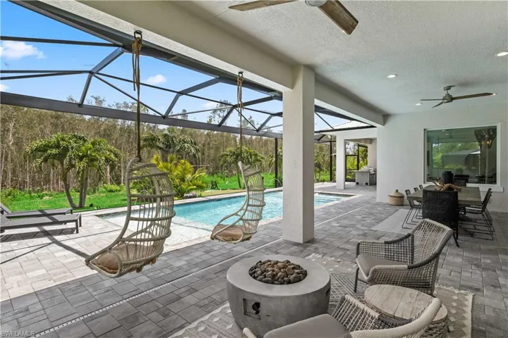 View of swimming pool with an outdoor fire pit, ceiling fan, a lanai, and a patio for sitting and outdoor dining.