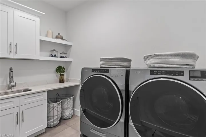 Laundry room with sink, washer and dryer, cabinets, and light tile floors