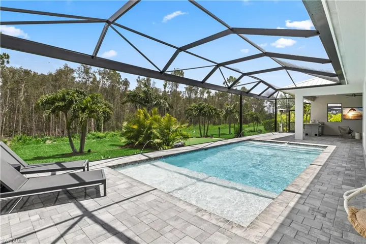 View of swimming pool featuring Custom screened pool enclosure and lanai patio area