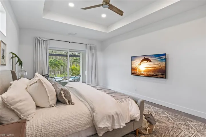 Bedroom featuring a raised ceiling, ceiling fan, and access to outside
