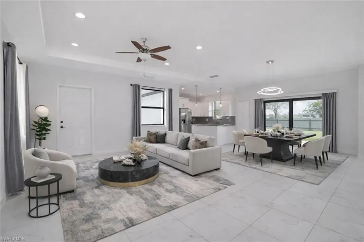 Virtually staged open concept living area featuring ceiling fan, recessed lighting, and a tray ceiling