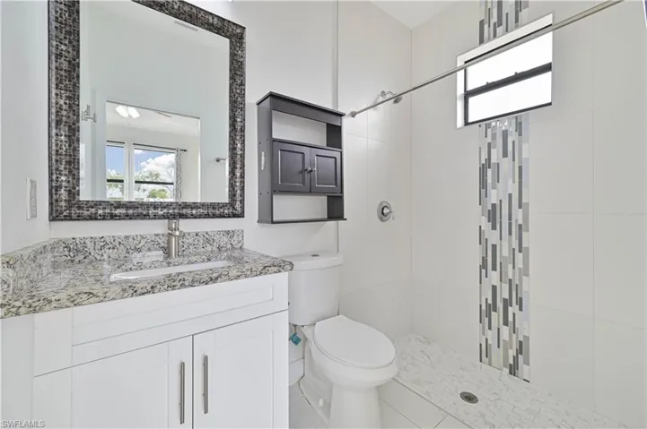 Primary bathroom featuring vanity with custom mirror and a large shower with decorative tile