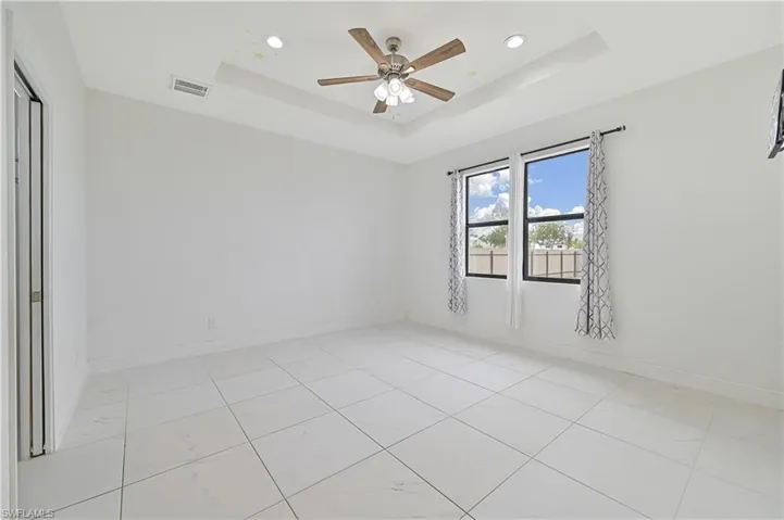 Primary bedroom with a ceiling fan and recessed lighting, large window, and walk in closet