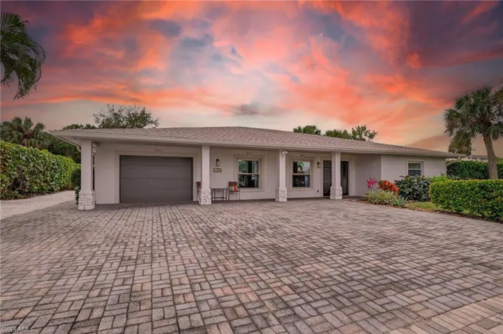 Ranch-style house featuring a garage, stucco siding, decorative driveway, and covered porch