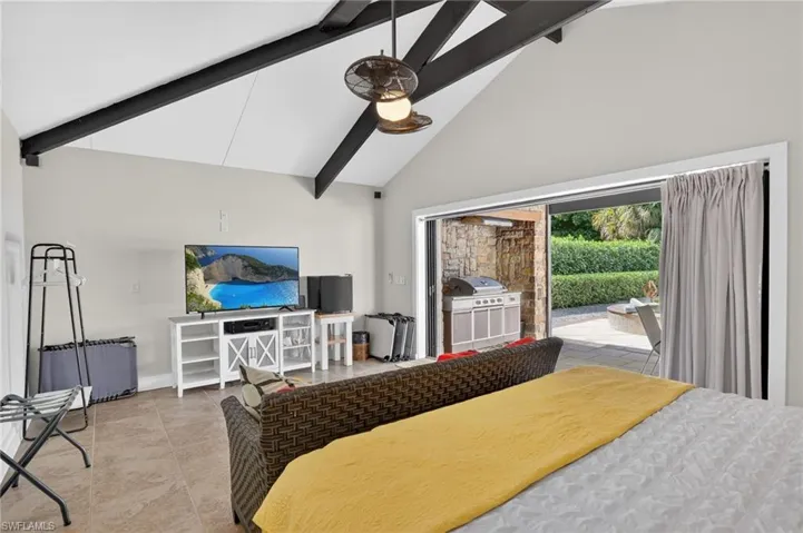 Bedroom with access to exterior, high vaulted ceiling, and beam ceiling