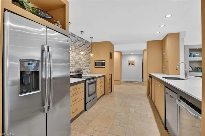 Kitchen featuring appliances with stainless steel finishes, recessed lighting, light stone countertops, stone tile floors, and pendant lighting