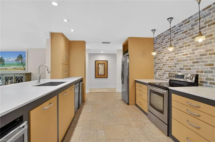 Kitchen with stainless steel appliances, light stone counters, stone tile flooring, pendant lighting, and recessed lighting