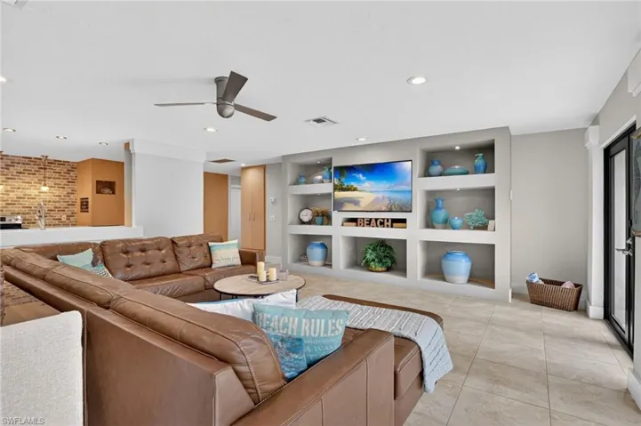 Living area with built in shelves, ceiling fan, recessed lighting, and light tile patterned floors