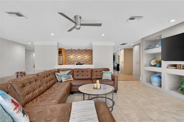 Living room with built in features, a ceiling fan, recessed lighting, and light tile patterned floors