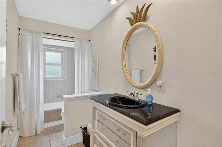 Bathroom featuring vanity, shower / bath combo with shower curtain, a textured wall, and light tile patterned flooring