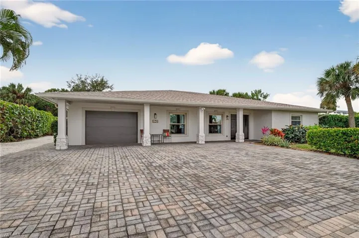 Ranch-style home featuring an attached garage, stucco siding, and decorative driveway