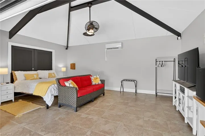 Bedroom featuring beamed ceiling, high vaulted ceiling, and a wall unit AC