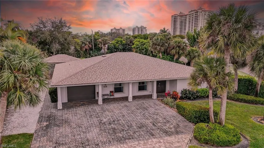View of front of house with an attached garage, a shingled roof, decorative driveway, and a front yard