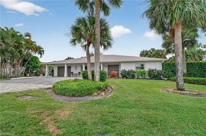 Ranch-style home featuring decorative driveway, a front yard, an attached garage, and stucco siding
