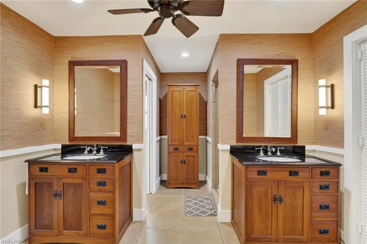 Full bath with two vanities, a stall shower, ceiling fan, light tile patterned floors, and a closet