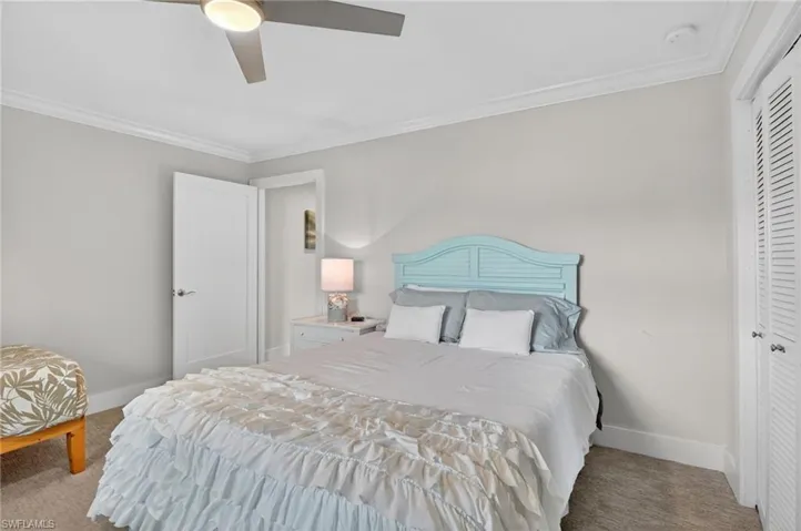 Carpeted bedroom with ornamental molding, a ceiling fan, and a closet