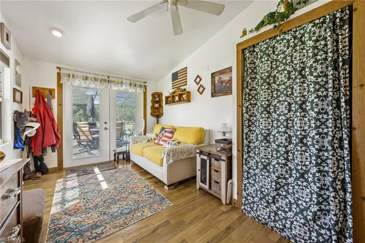 Bedroom featuring access to outside, wood finished floors, french doors, lofted ceiling, and ceiling fan