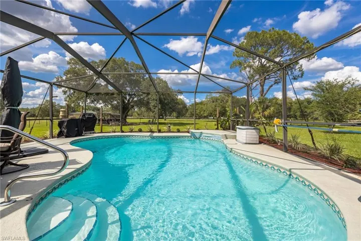 Swimming pool featuring a patio, glass enclosure, and a lawn