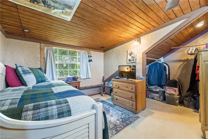 Bedroom featuring a textured wall, wood ceiling, and carpet floors