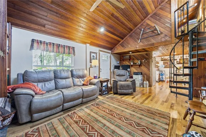 Living room featuring wooden ceiling, stairway, wood finished floors, lofted ceiling, and wood walls