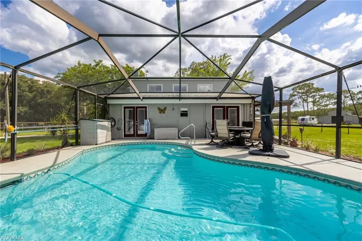 Swimming pool with french doors, a patio area, and a lanai