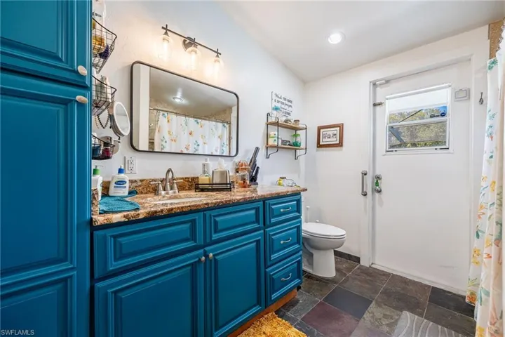 Full bathroom with vanity, stone finish floors, and a shower with shower curtain