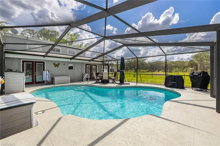 Outdoor pool featuring french doors, a patio area, area for grilling, and glass enclosure