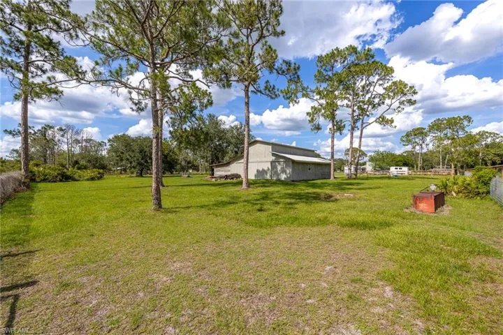 View of grassy yard with an outbuilding and a pole building