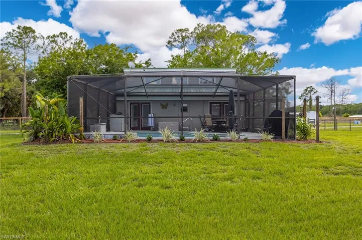 Rear view of property with a yard, a lanai, a patio area, and a swimming pool