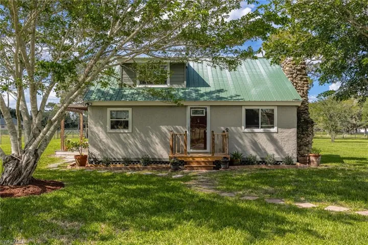 View of front of property with stucco siding, a front yard, and a metal roof