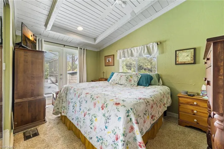 Carpeted bedroom featuring access to outside, french doors, wood ceiling, lofted ceiling, and a textured wall