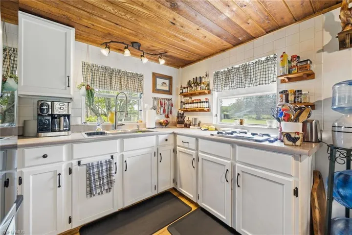Kitchen with open shelves, white cabinets, light countertops, and wood ceiling