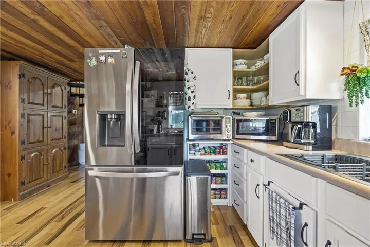 Kitchen featuring wooden ceiling, appliances with stainless steel finishes, light wood-style flooring, open shelves, and light countertops