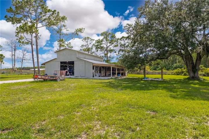 View of grassy yard featuring a pole building and an outdoor structure