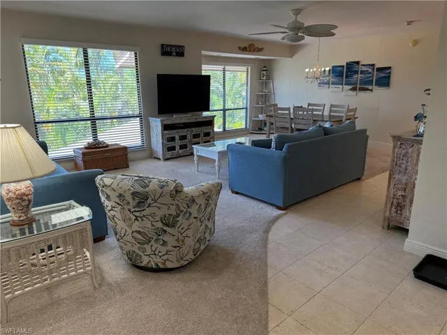 Living area with light tile patterned floors, a ceiling fan, light colored carpet, and a chandelier