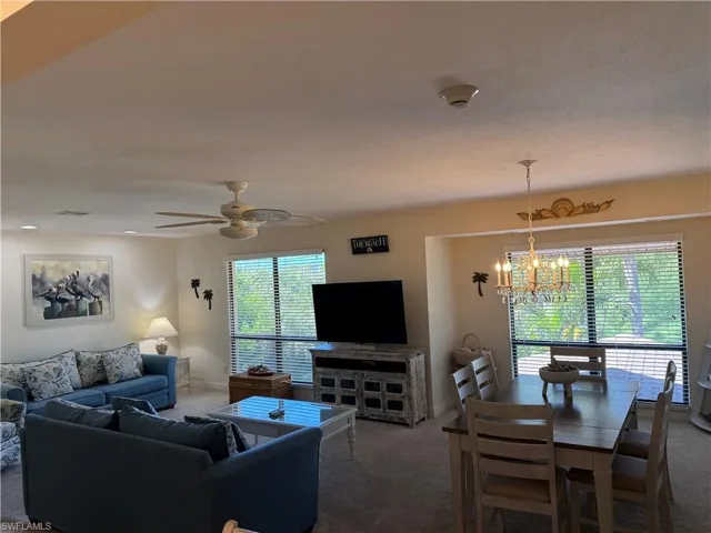 Living area featuring carpet floors, a chandelier, and ceiling fan