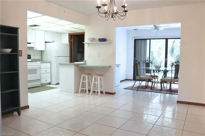 Kitchen featuring white appliances, open shelves, white cabinetry, a kitchen breakfast bar, and a peninsula