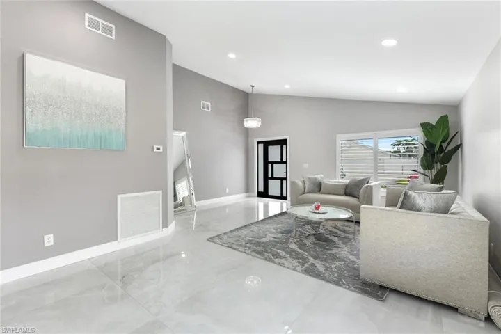 Living room with lofted ceiling, recessed lighting, and marble tiled flooring