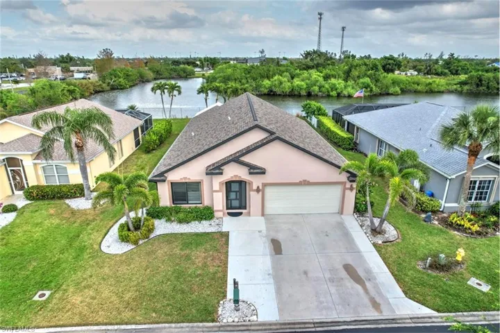 View of front of home featuring stucco siding, a water view, concrete driveway, an attached garage, and a front lawn
