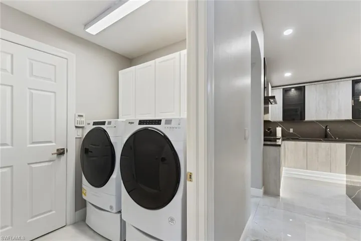 Laundry area with washing machine and clothes dryer, cabinet space, arched walkways, and recessed lighting