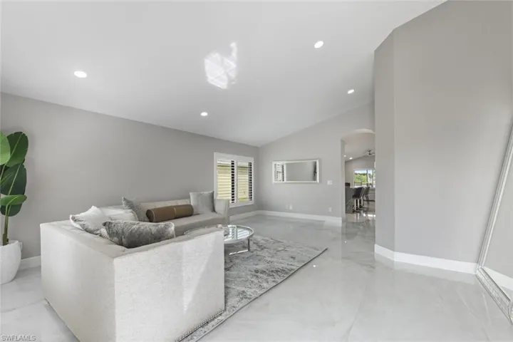 Living area featuring arched walkways, recessed lighting, and vaulted ceiling